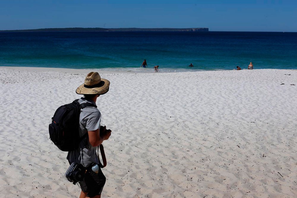 chico con un sombrero de paja de espaldas y mirando al mar en una playa